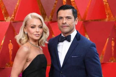 kelly and husband mark on the red carpet . kelly wearing a black strapless gown and mark in a blue tuxedo 